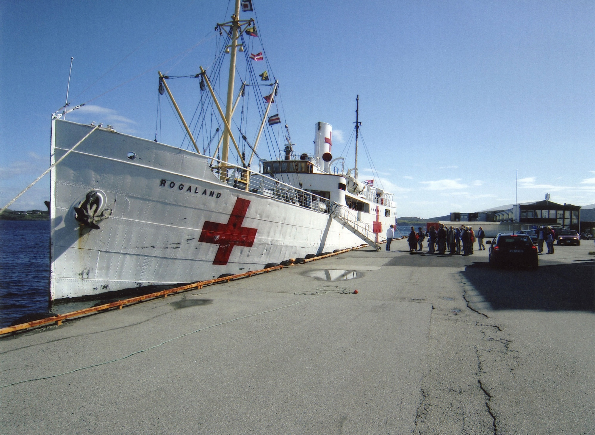 M/S "Rogaland" til kai i Kopervik ... KOH arrangerte historisk fjordtur med M/S "Rogaland" for andre år på rad ... Turen gikk dette året inn Førdesfjorden ... 100 passasjerer fikk en vellykket tur med god mat og drikke ... Det hvite skroget med Røde Kors-merket kommer av at fartøyet har deltatt som hospitalskip i en stor filminnspilling om D-dagen i Frankrike  ...  Se hefte 26, side 49