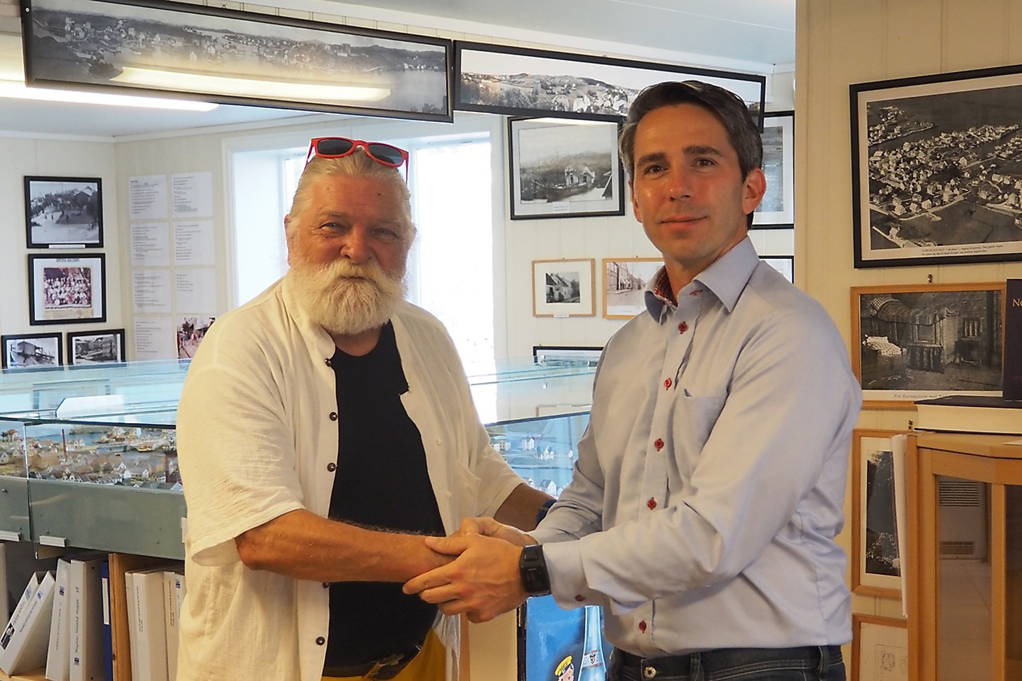 Gunnar Palander og lederen av KOH Harald Bredahl tar hverandre i hendene etter at dokumentet med alle gavene var presentert ... Gavene består blant annet av malerier av kjente norske kunstnere, noen møbler, farens fortjenestemedalje fra siste verdenskrig, modellskuter laget av bestefaren og mere ...  Se artikkel i hefte nr. 26, side 47  Fra venstre: Gunnar Palander og Harald Bredahl