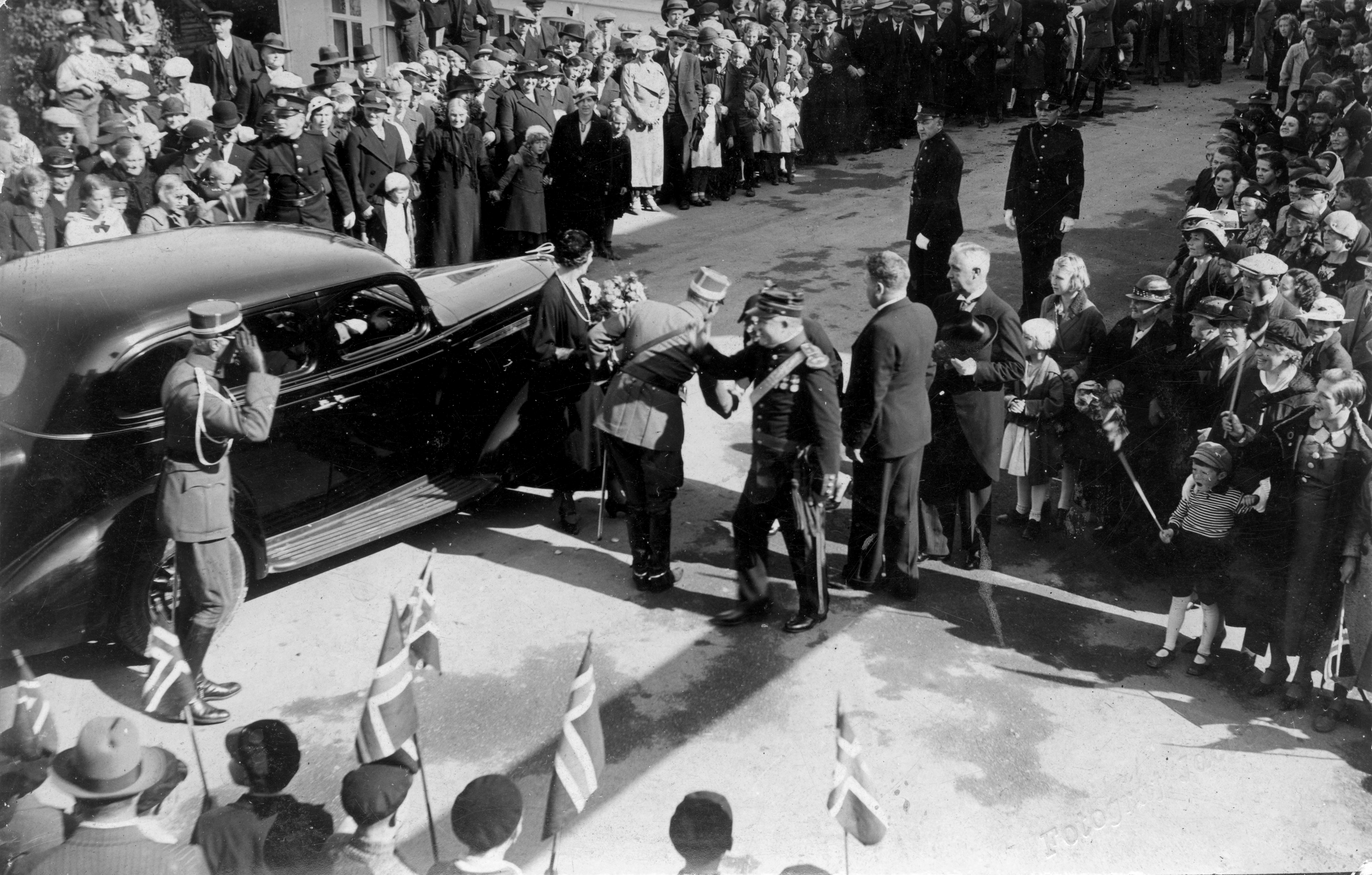 Karmøyutstillingen 1936 Kronprinsparet ankommer Kopervik og utstillingen ... Her blir paret tatt imot av byens prominente og andre oppmøtte i Hovedgaten ved hovedinngangen til utstillingen ......  Bl.a.: Kronprinsparet, ordfører Elias Sandvig og Nils O. Fjeldkårstad
